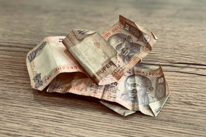 a pile of indian currency sitting on top of a wooden table