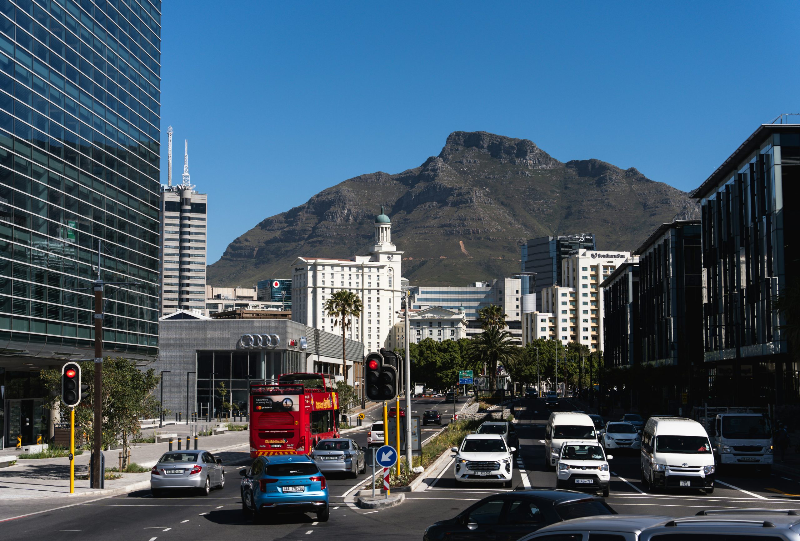 a red double decker bus driving down a street next to tall buildings